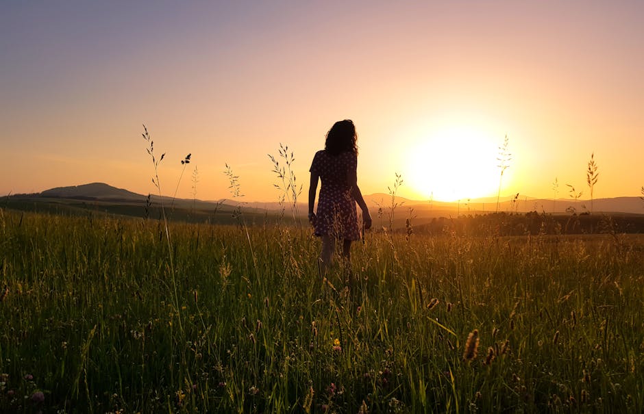 Silhouette of a person gently stretching during a beautiful sunrise over a field.